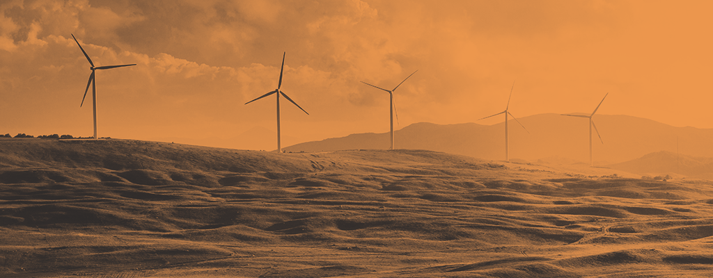 Wind turbines on rolling hills against an orange sunset sky symbolizing sustainable energy in Africa